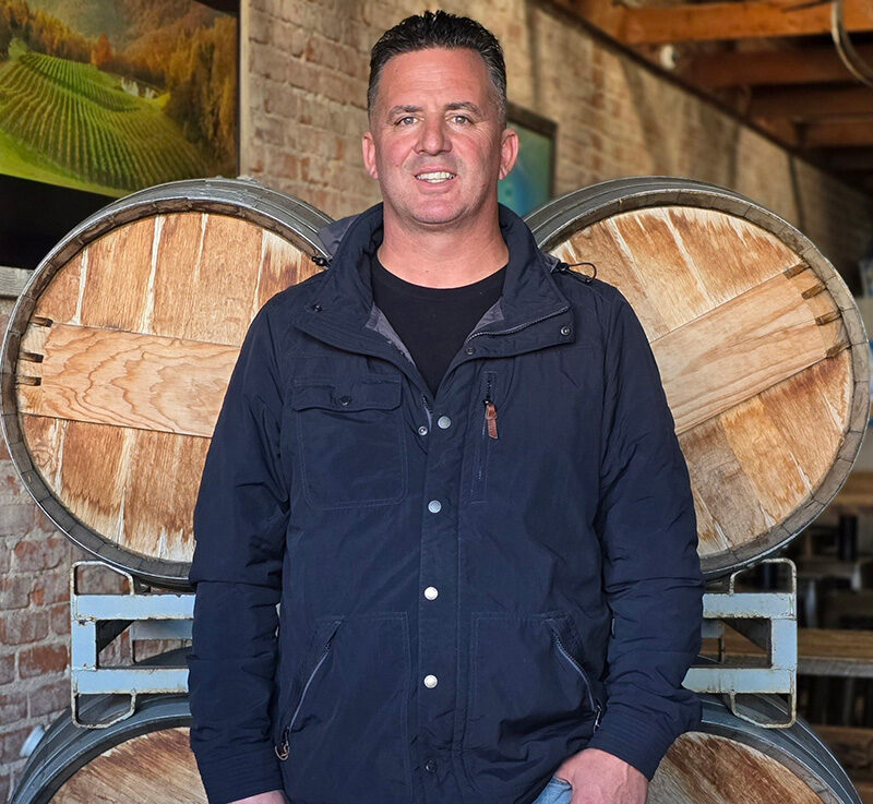 Will Burtner in front of oak barrels